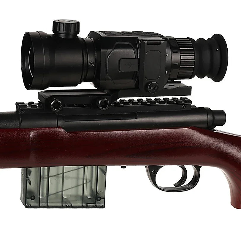 Digital night vision scope mounted on a rifle with a dark wood stock