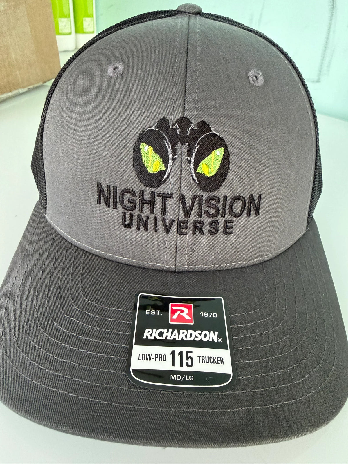 Grey Richardson 115 low-profile trucker hat featuring Night Vision Universe embroidered logo.