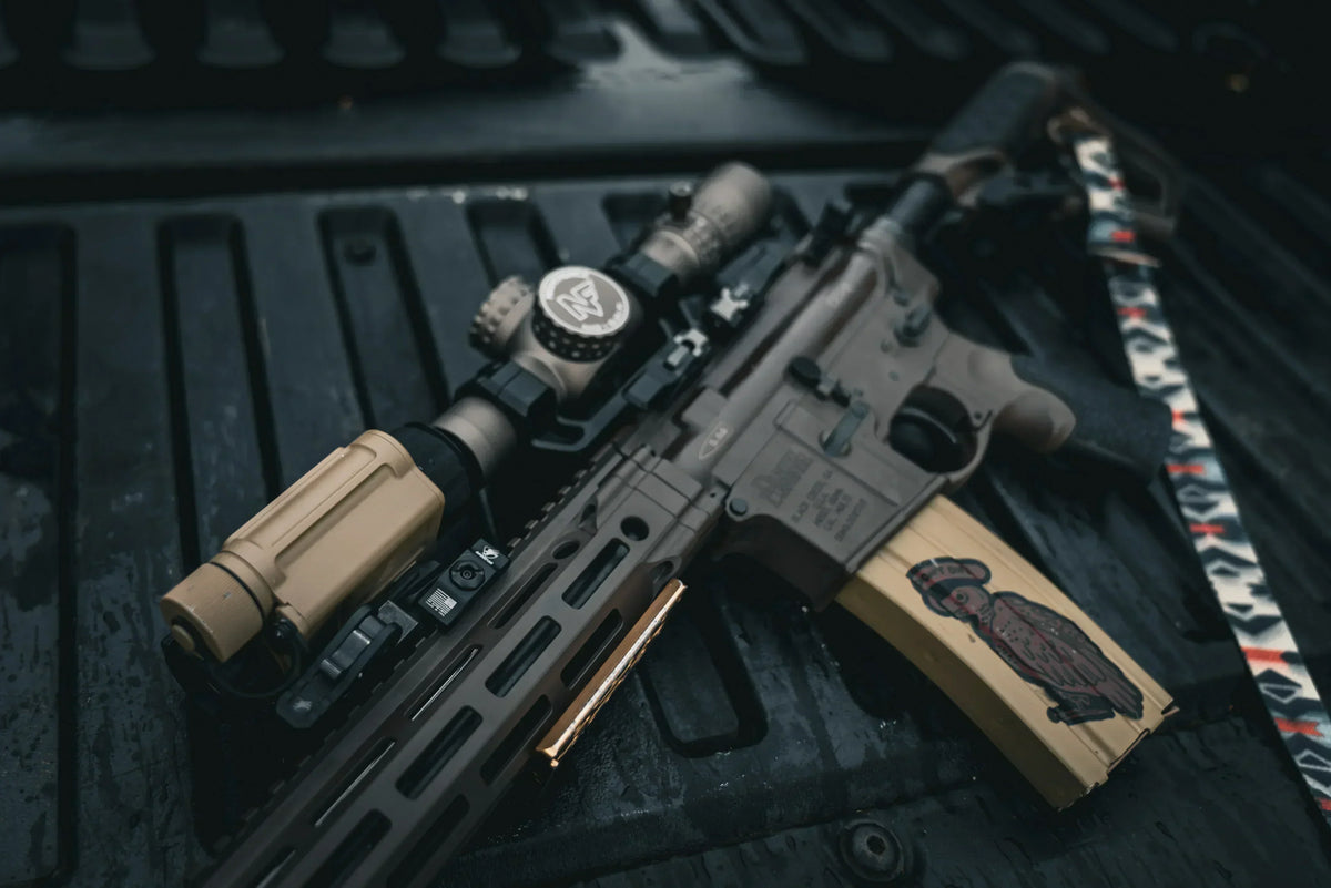 Tan tactical rifle with InfiRay optic and flashlight on a black textured surface