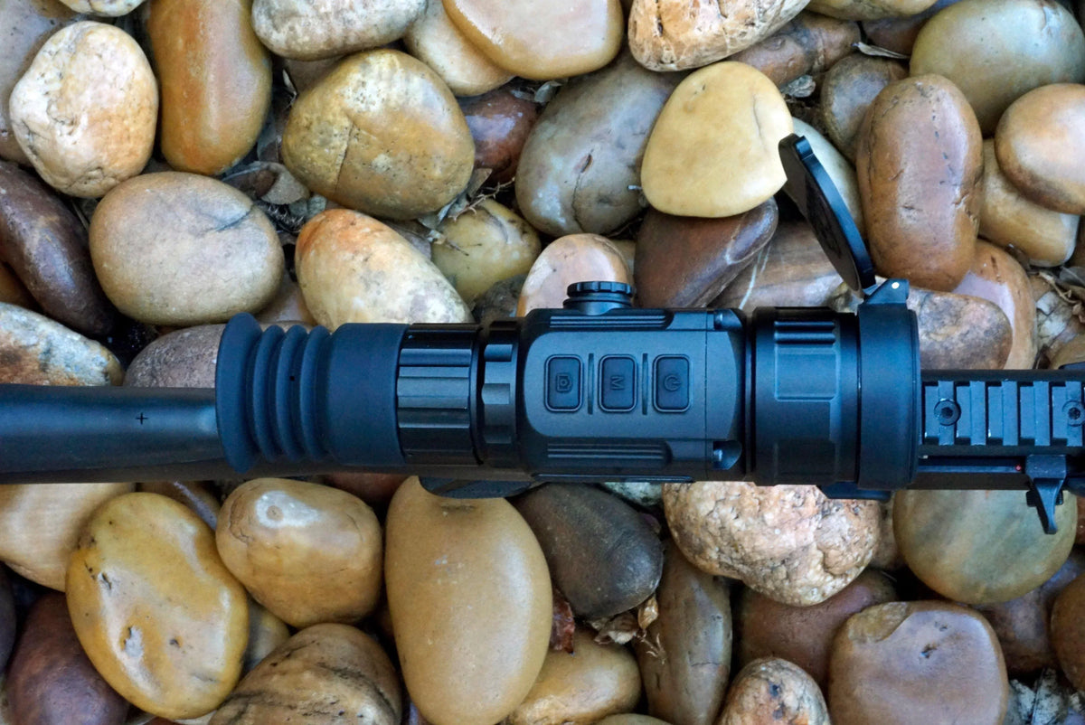 Thermal scope with control buttons and rail mount on river rocks background